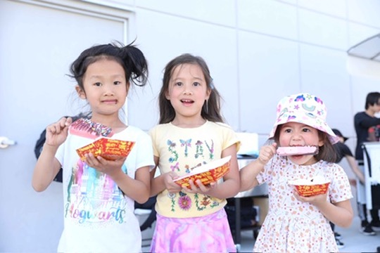 Three kids enjoying dipped paletas at a Paleta Bar event